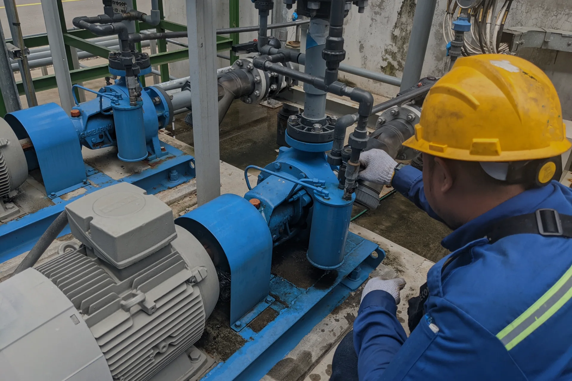 Arbetare vid blå pumpmaskin